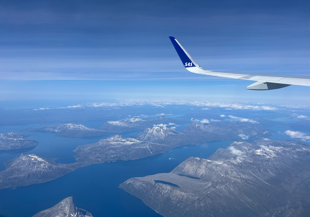 Der Blick aus dem Flugzeugfenster auf die zerklüftete Küste Grönlands – selbst beim Rückflug fällt der Abschied schwer.